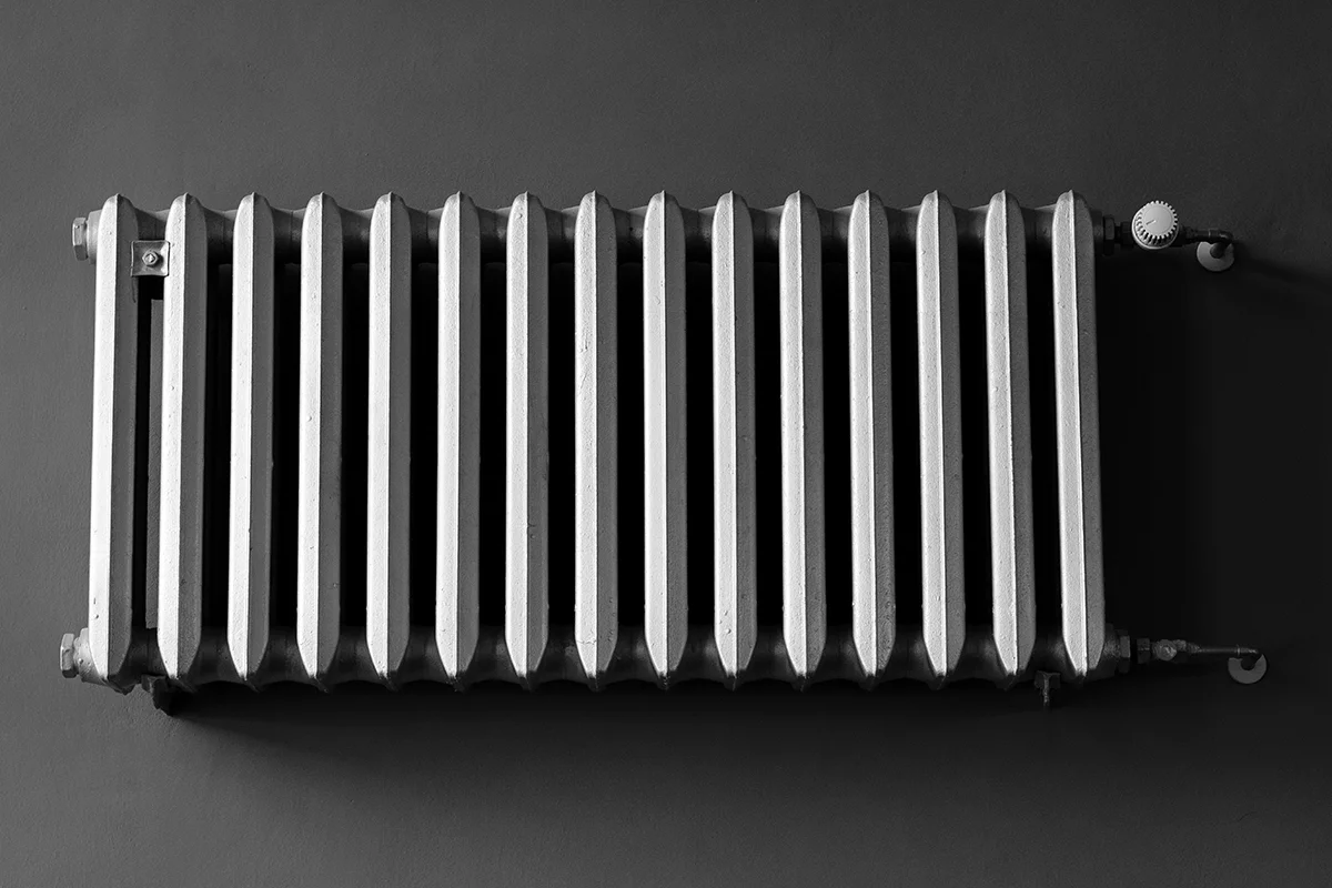 Classic wall-mounted metal radiator against dark wall.