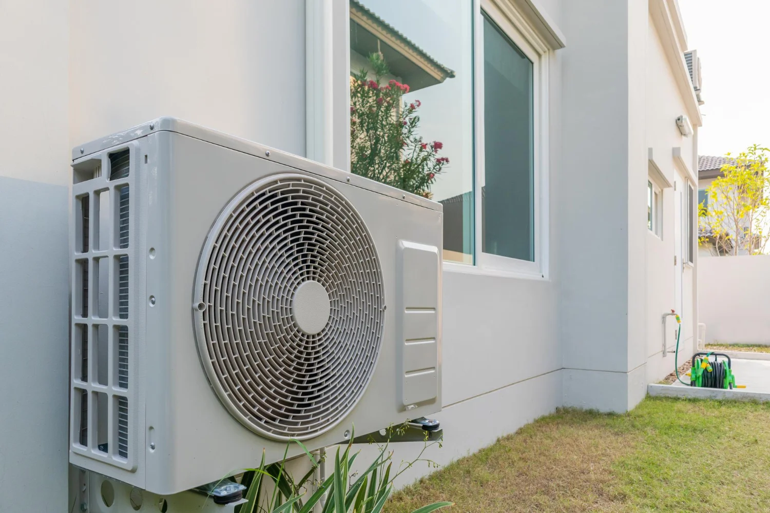 Outdoor air conditioning unit on house exterior wall.