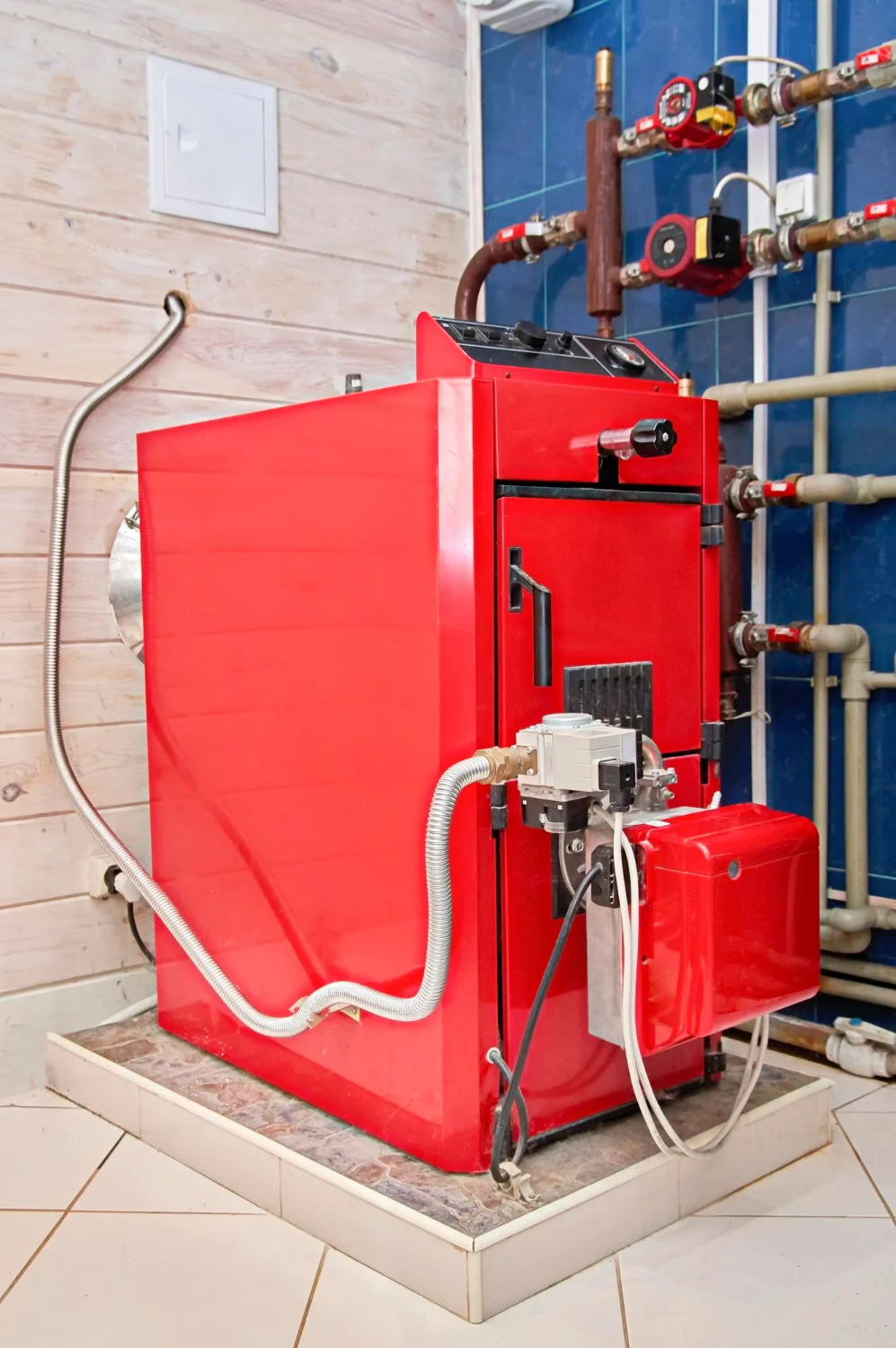 Red industrial boiler in utility room.